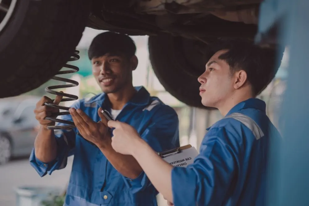 Two mechanics repairing a car