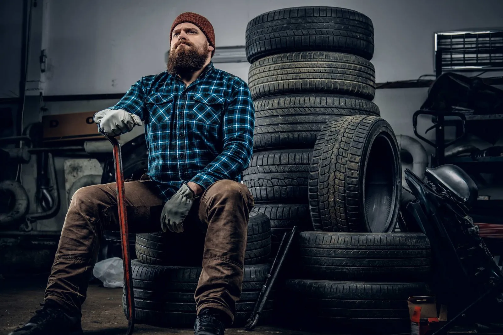 Mechanic sitting among stacked tyres
